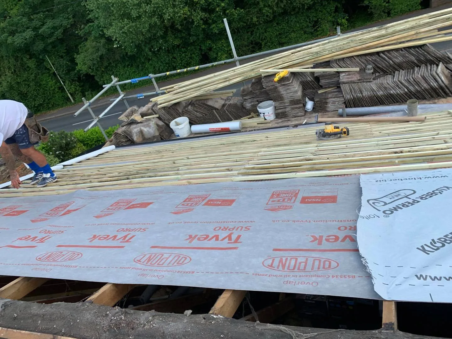 A roof stripped back to membrane and new battens with tiles stacked ready