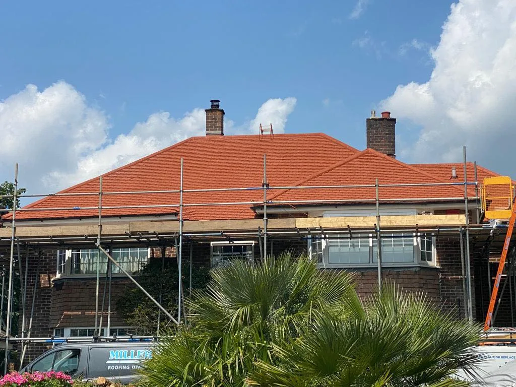 A house with a freshly re-tiled red roof, still under scaffolding, with the Miller 'N' Shine van in the drive