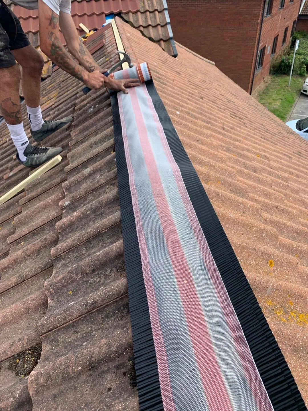 A dry-fix ridge system being fitted along the top of a tiled roof