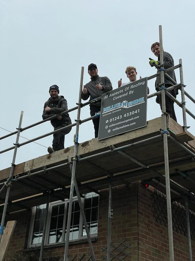 The Miller 'N' Shine team on scaffolding outside a house, beside a board that reads All Aspects Of Roofing Covered By Miller 'N' Shine