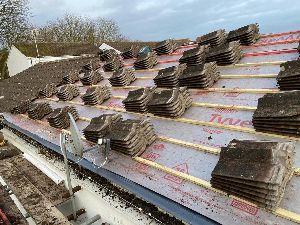 Stacks of new concrete tiles laid out on battens over breathable membrane, ready for fixing